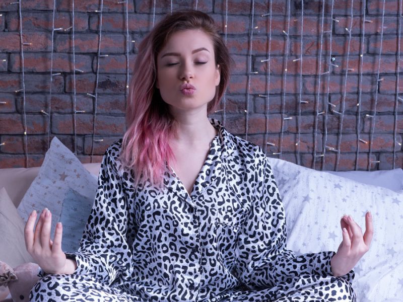 meditating-woman-leopard-pajamas-against-brick-wall